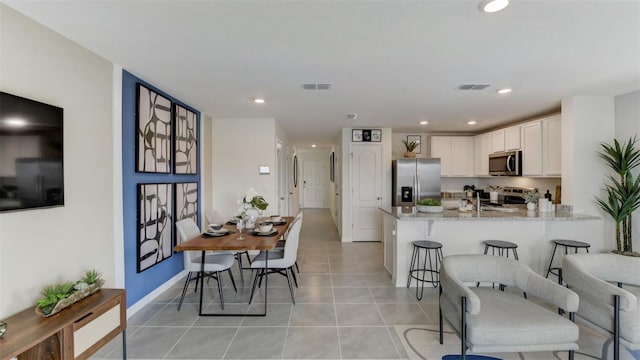 2975 Brie Hammock Bnd, Saint Cloud, FL 34773 - kitchen featuring light stone countertops, stainless steel appliances, white cabinetry, a peninsula, and visible vents