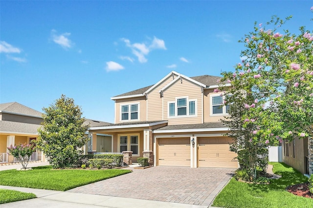 craftsman house with an attached garage, decorative driveway, and a front yard