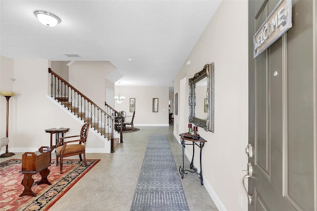 entrance foyer featuring baseboards, a notable chandelier, stairway, and visible vents