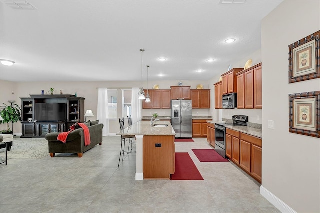 kitchen featuring hanging light fixtures, stainless steel appliances, a kitchen breakfast bar, open floor plan, and visible vents