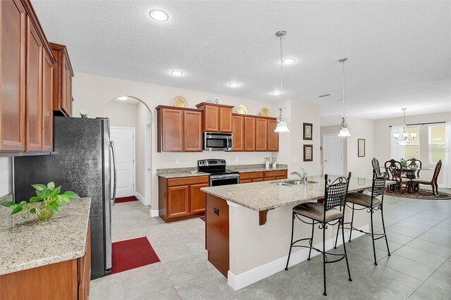 kitchen featuring a sink, stainless steel appliances, a breakfast bar area, and brown cabinets