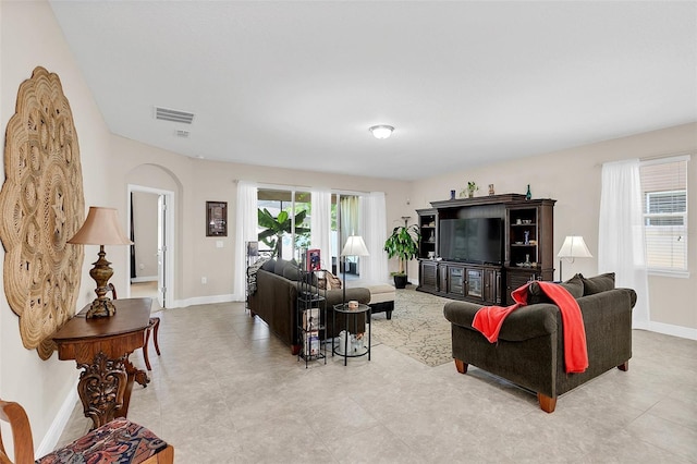 living room featuring visible vents, baseboards, and arched walkways