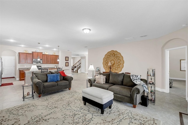 living area with arched walkways, stairs, baseboards, and visible vents