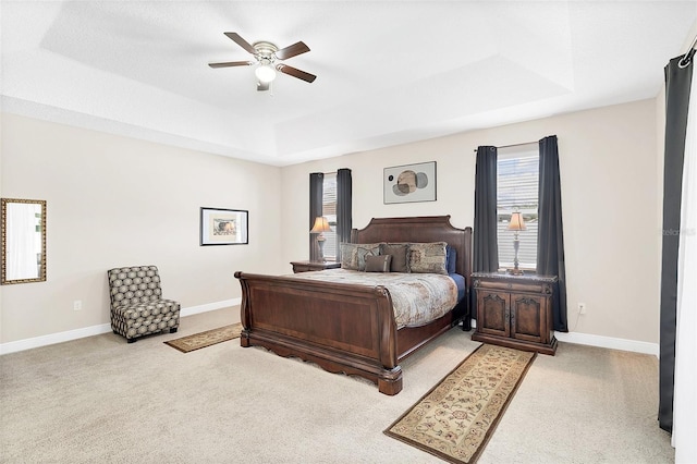 bedroom with a tray ceiling, carpet flooring, baseboards, and ceiling fan