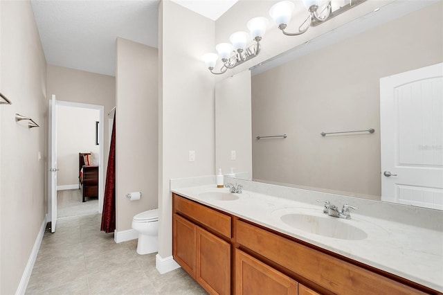 bathroom featuring toilet, baseboards, double vanity, and a sink