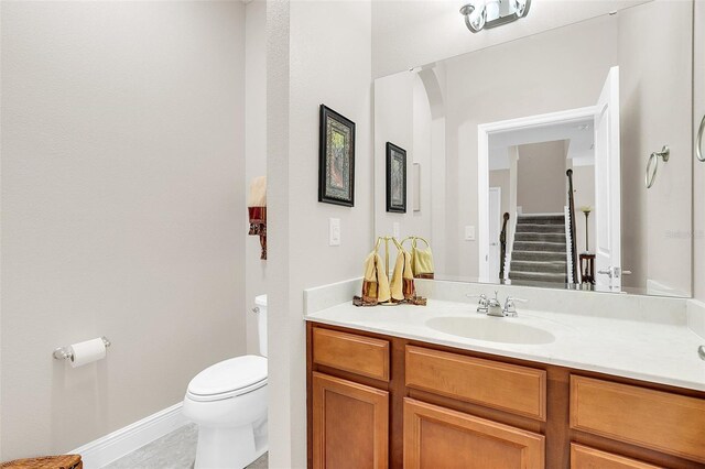 bathroom featuring toilet, baseboards, and vanity