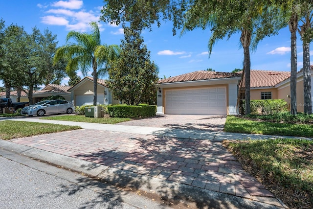 11908 Fiore Dr Unit 1, Orlando, FL 32827 - view of front of house with a tile roof, decorative driveway, an attached garage, stucco siding, and cooling unit