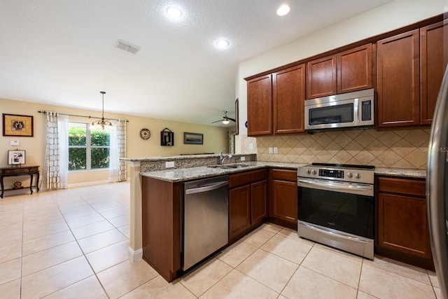 11908 Fiore Dr Unit 1, Orlando, FL 32827 - kitchen with appliances with stainless steel finishes, a sink, a peninsula, backsplash, and light tile patterned floors