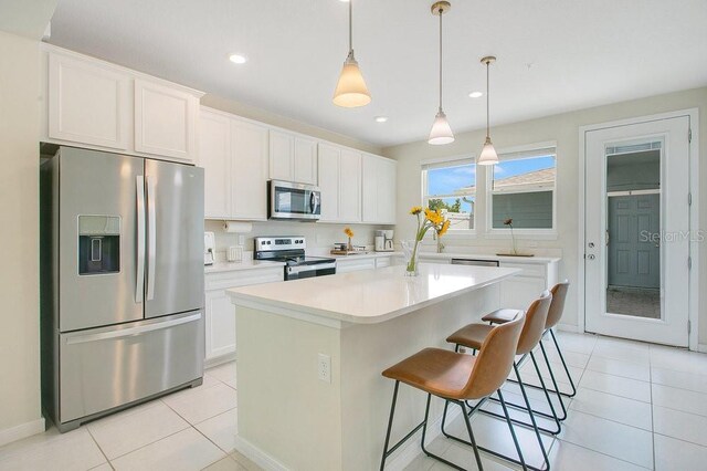 10940 Leafshore Loop, Orlando, FL 32829 - kitchen with appliances with stainless steel finishes, light tile patterned flooring, a center island, white cabinetry, and recessed lighting