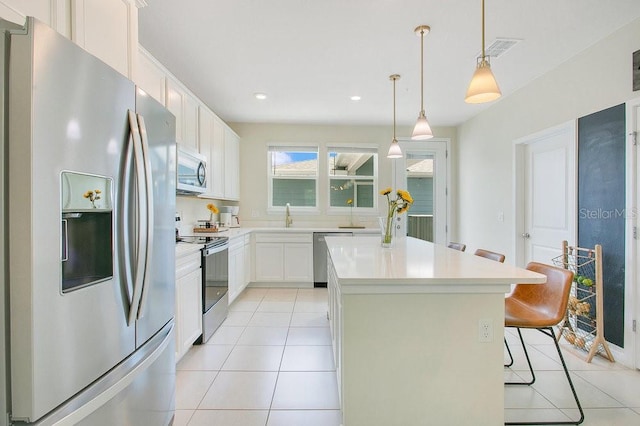 10940 Leafshore Loop, Orlando, FL 32829 - kitchen featuring appliances with stainless steel finishes, light tile patterned floors, a center island, light countertops, and white cabinets