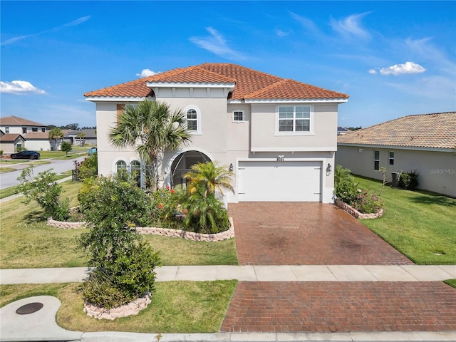 mediterranean / spanish-style house with decorative driveway, stucco siding, a tiled roof, a garage, and a front lawn