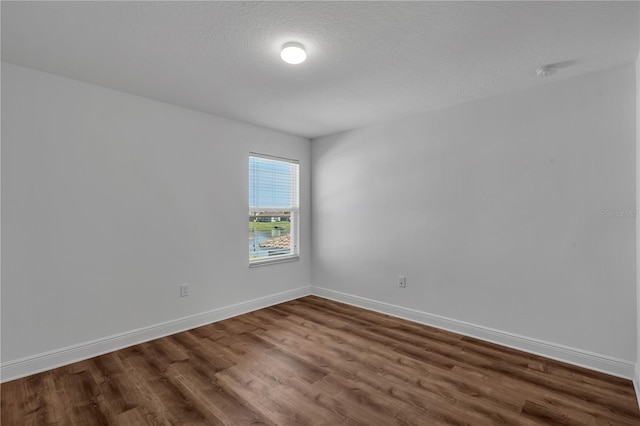 empty room with dark wood-type flooring, baseboards, and a smoke detector