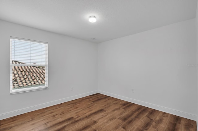 spare room featuring wood finished floors and baseboards
