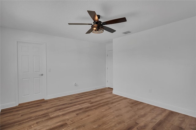 unfurnished room with ceiling fan, wood finished floors, and baseboards