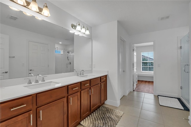 bathroom with tile patterned flooring, a shower stall, double vanity, and baseboards