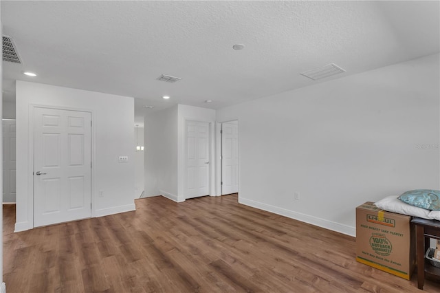 empty room featuring wood finished floors, baseboards, recessed lighting, and a textured ceiling