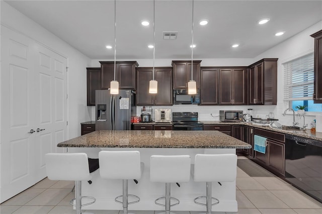 kitchen with black appliances, a breakfast bar, a center island, dark stone countertops, and recessed lighting