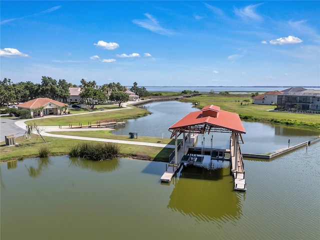 dock area with a water view, a lawn, and boat lift