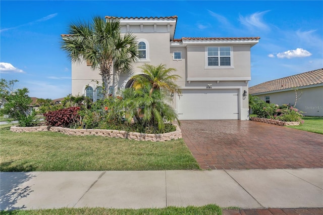 view of front of house featuring stucco siding, decorative driveway, an attached garage, a tiled roof, and a front lawn
