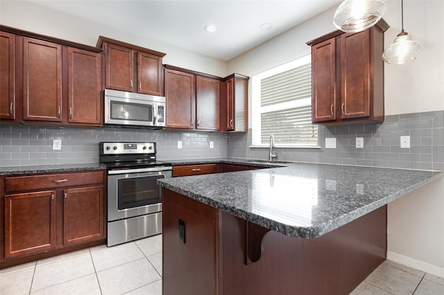 kitchen featuring stainless steel appliances, a sink, a peninsula, light tile patterned floors, and a kitchen breakfast bar