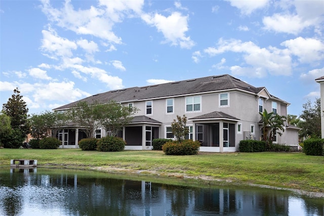 rear view of house featuring a sunroom, a water view, stucco siding, and a yard