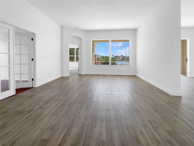 5154 51st Ln W, Bradenton, FL 34210 - unfurnished living room featuring arched walkways, baseboards, and wood finished floors