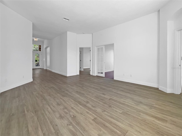 5154 51st Ln W, Bradenton, FL 34210 - unfurnished living room featuring arched walkways, baseboards, visible vents, and wood finished floors
