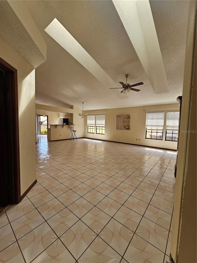 unfurnished room with a textured ceiling, a ceiling fan, baseboards, and light tile patterned floors