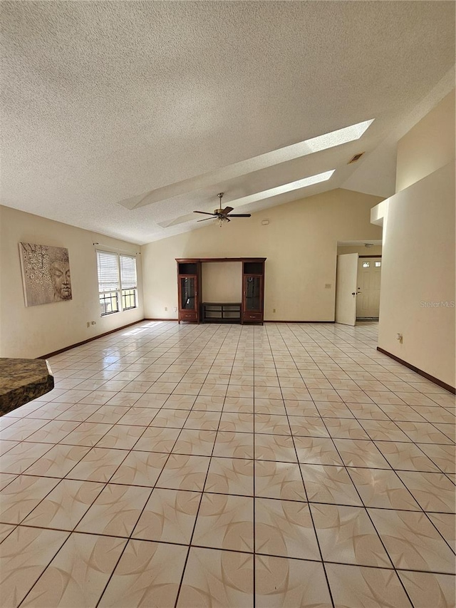 unfurnished living room with a skylight, a textured ceiling, lofted ceiling, light tile patterned flooring, and a ceiling fan