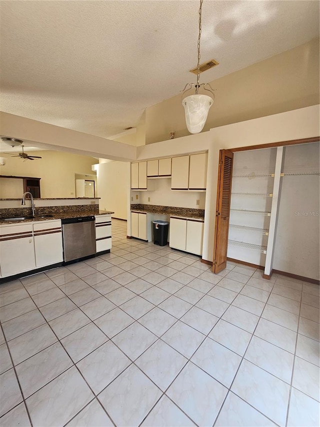 kitchen featuring dishwasher, a sink, dark countertops, lofted ceiling, and pendant lighting