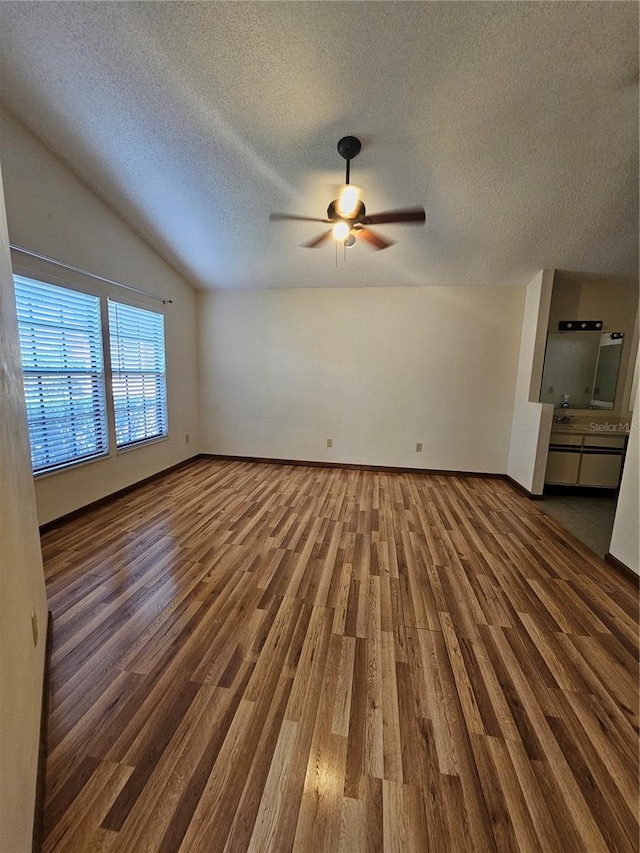 unfurnished living room featuring wood finished floors, a ceiling fan, a textured ceiling, and lofted ceiling