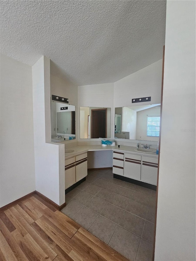 full bathroom with a textured ceiling, vanity, and wood finished floors