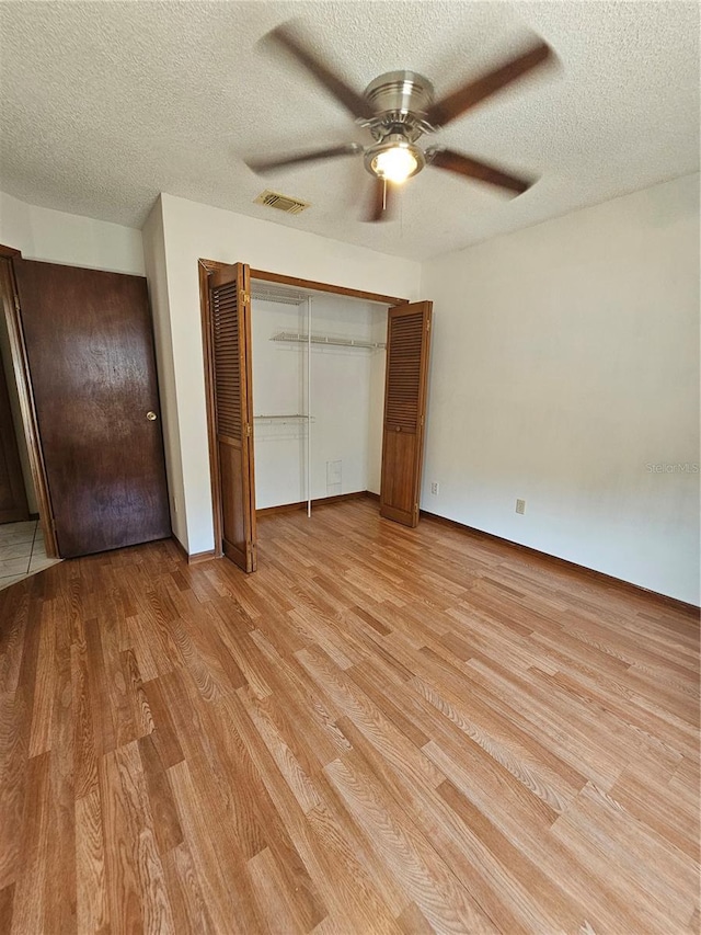 unfurnished bedroom featuring light wood-style floors, a textured ceiling, a ceiling fan, baseboards, and a closet
