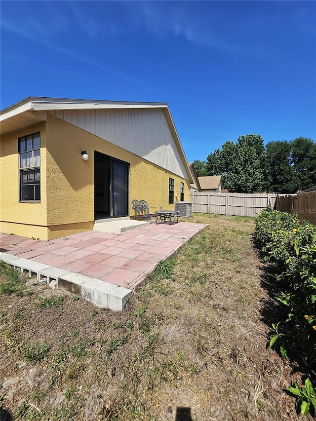 rear view of property with a patio, fence, and stucco siding
