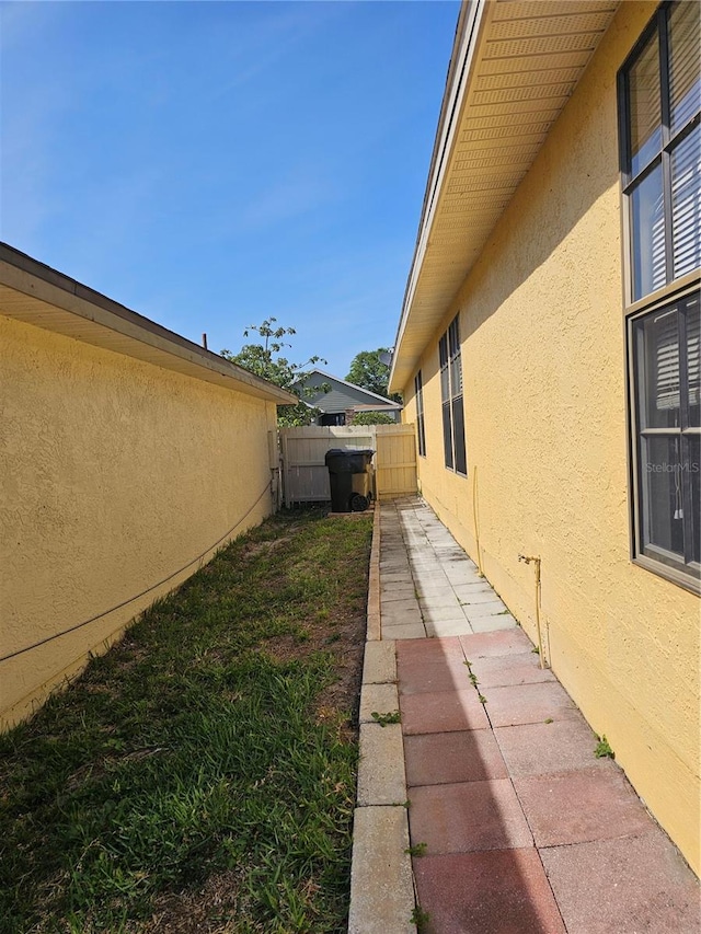 view of home's exterior with stucco siding and fence