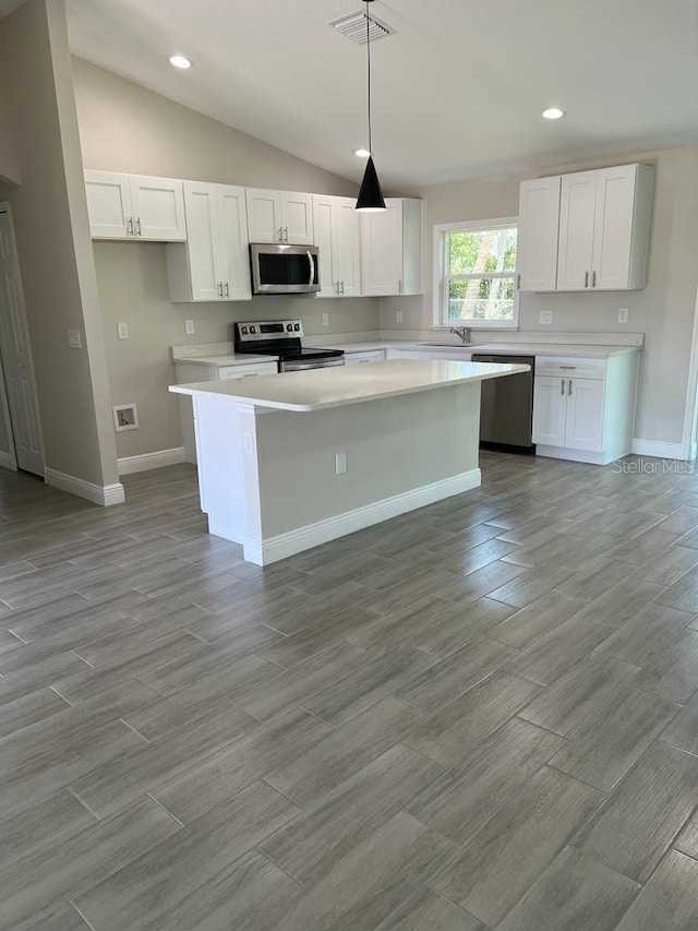 kitchen with a sink, visible vents, white cabinets, a kitchen island, and appliances with stainless steel finishes