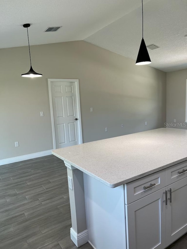 kitchen featuring white cabinets, visible vents, baseboards, dark wood-type flooring, and lofted ceiling