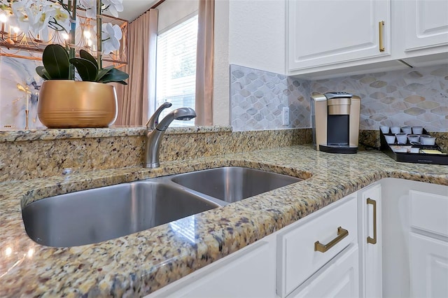 2624 Daulby St, Kissimmee, FL 34747 - kitchen view of a sink, backsplash, light stone countertops, and white cabinetry