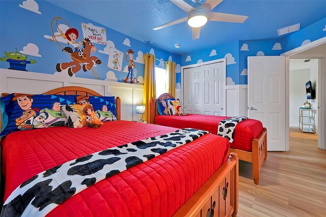 2624 Daulby St, Kissimmee, FL 34747 - bedroom featuring light wood-type flooring, a closet, wainscoting, a ceiling fan, and a decorative wall