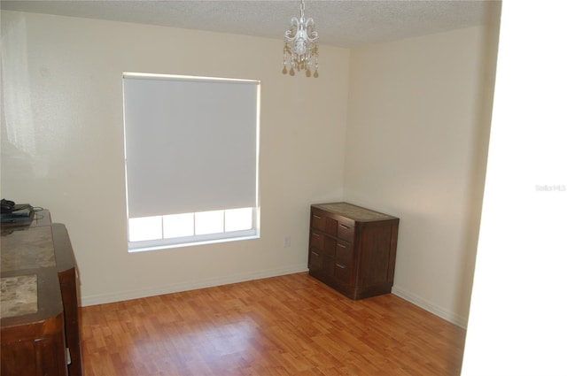 1644 Cypress Woods Cir, Saint Cloud, FL 34772 - unfurnished room featuring a chandelier, a textured ceiling, baseboards, and light wood-style floors