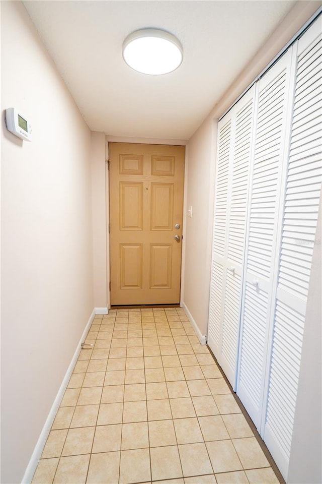 corridor featuring baseboards and light tile patterned flooring
