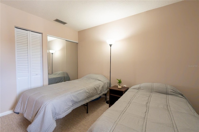 carpeted bedroom featuring two closets, baseboards, and visible vents