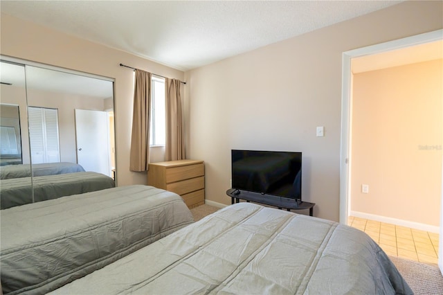 tiled bedroom with a closet and baseboards