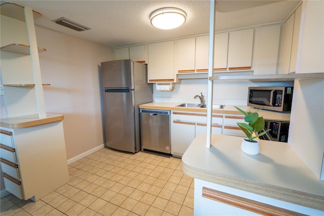 kitchen with a sink, stainless steel appliances, white cabinetry, visible vents, and light countertops
