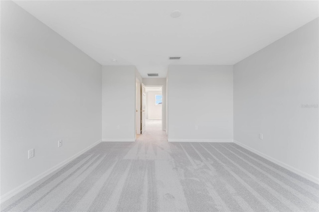 empty room featuring light carpet, baseboards, and visible vents