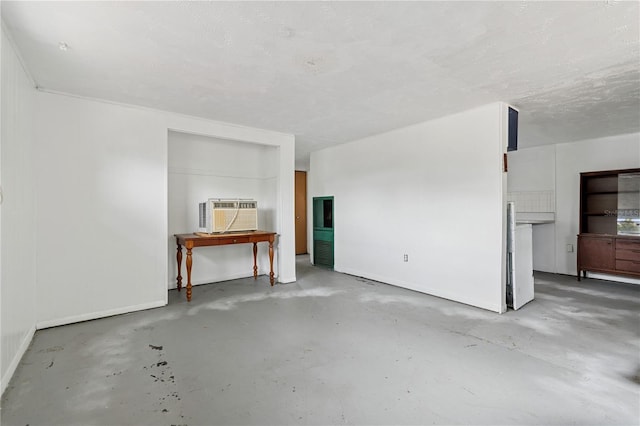 unfurnished living room with concrete flooring, baseboards, and a wall mounted AC