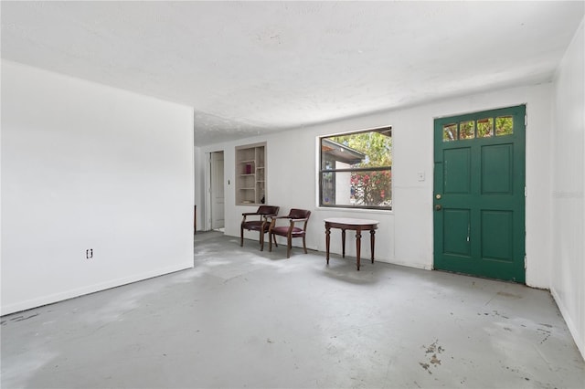 entrance foyer with unfinished concrete flooring and baseboards