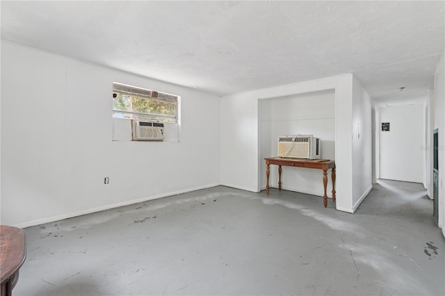 empty room featuring a wall mounted AC, baseboards, cooling unit, and concrete floors