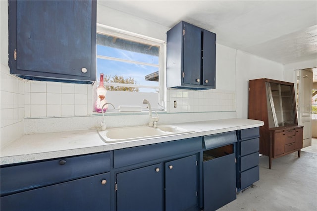 kitchen with decorative backsplash, concrete floors, a sink, and blue cabinetry