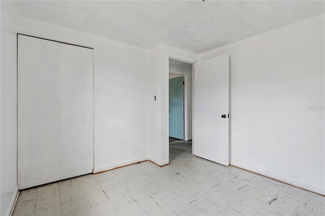 unfurnished bedroom featuring light floors, a closet, and baseboards